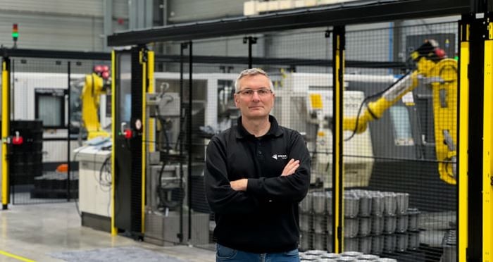 Homme debout avec les bras croisés dans une usine avec des machines en arrière-plan