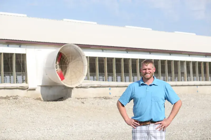 Man standing confidently in front of a large ventilation fan