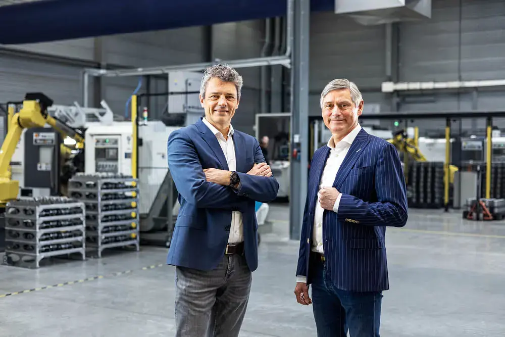 Two executives standing in a factory with machinery in the background