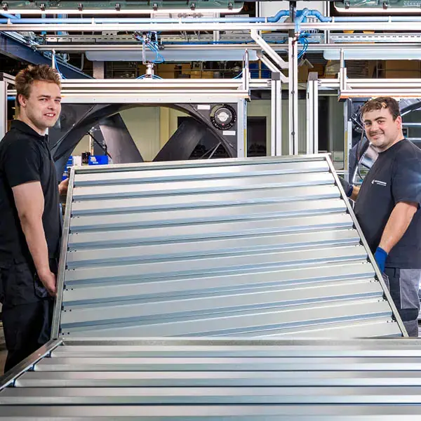 Employees working on end assembly of large metal component in a factory