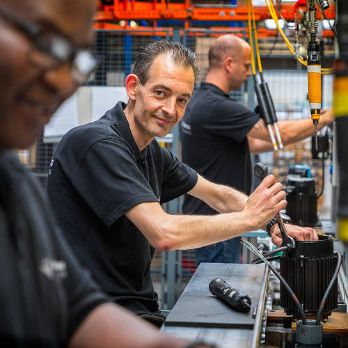 Employee using electric screwdriver in motor assembly process