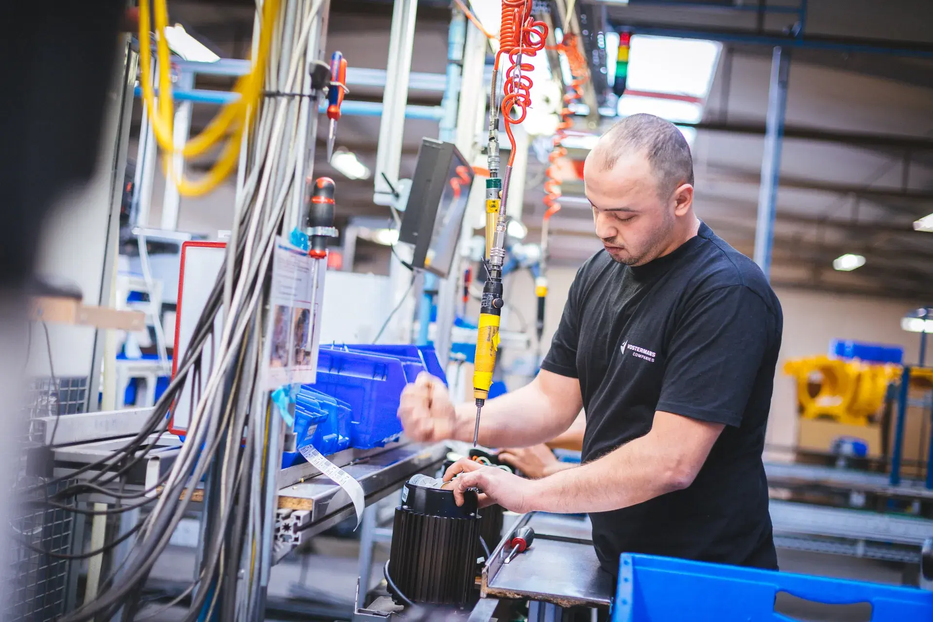 Employee assembling motor component on factory production line