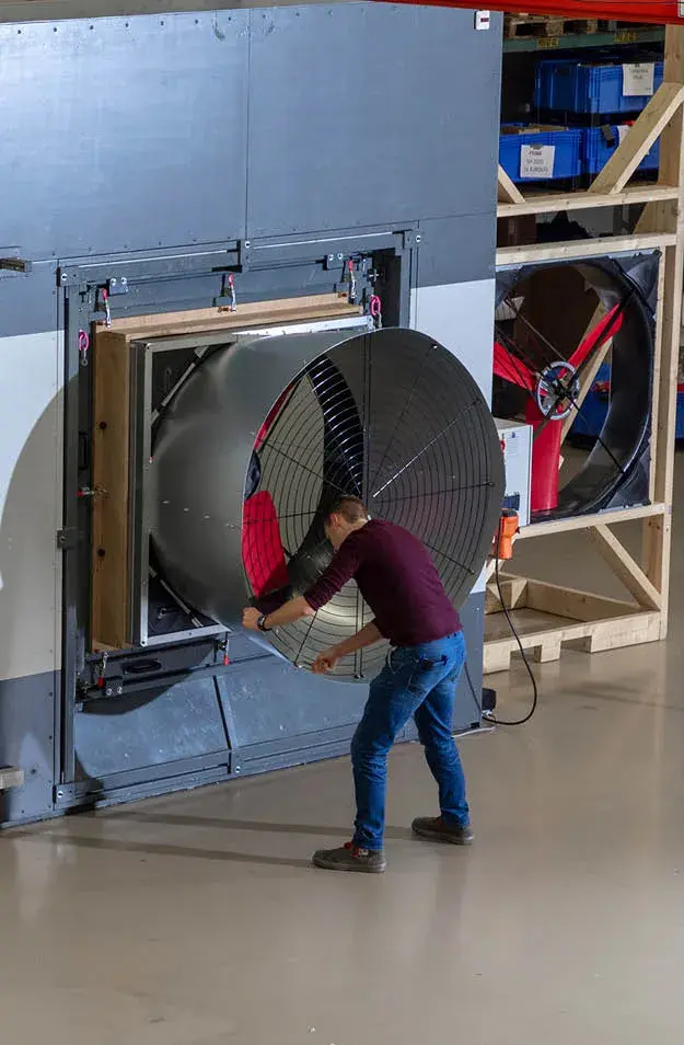 Employee testing large industrial ventilation fan in factory