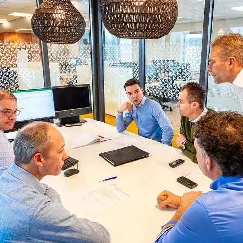 Sales team discussing strategy in modern office with laptop and documents on the table