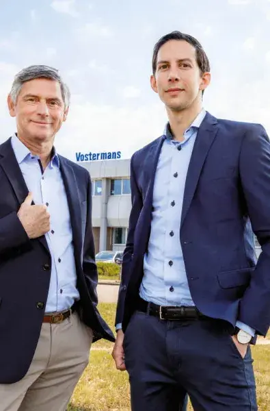 Twee mannen in zakelijke kleding poseren buiten een modern gebouw