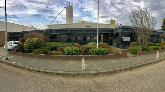 Modern building surrounded by plants under a cloudy sky